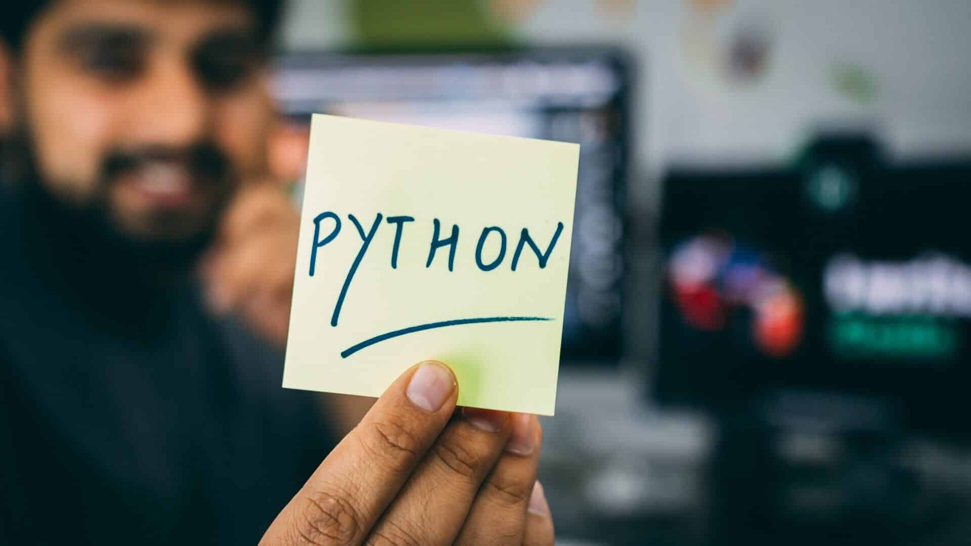 Elinde python yazılı kağıt tutan bir hintli yazılımcı